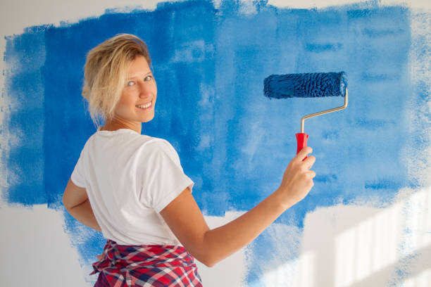 istock woman painting a wall with paint roller 1066487298