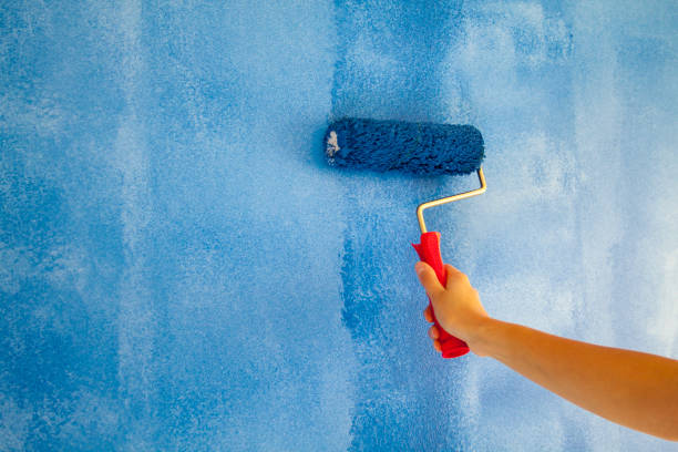istock woman painting a wall with paint roller 1066487316