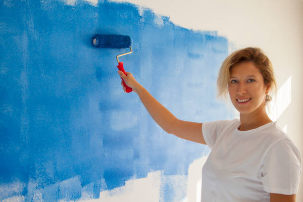 istock woman painting a wall with paint roller 1066487328