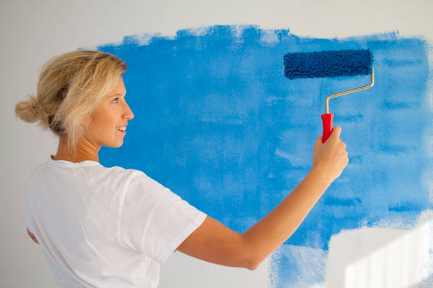 istock woman painting a wall with paint roller 1066487348