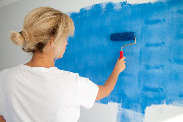 istock woman painting a wall with paint roller 1066487424