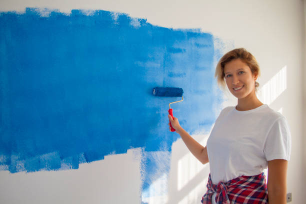istock woman painting a wall with paint roller 1066487446