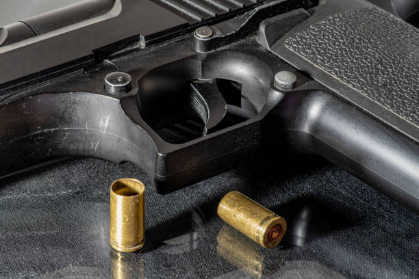istock Close up of a black hand gun with two empty brass shells 1066490024