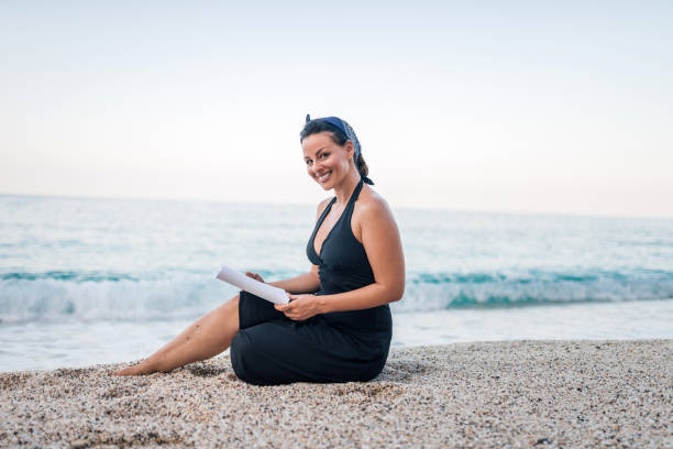 istock Beautiful woman reading a book on a beach. 1066494228