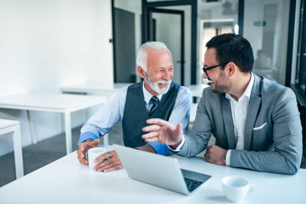 sonriendo a los hombres de negocios senior y junior en el trabajo. - nivel júnior fotografías e imágenes de stock