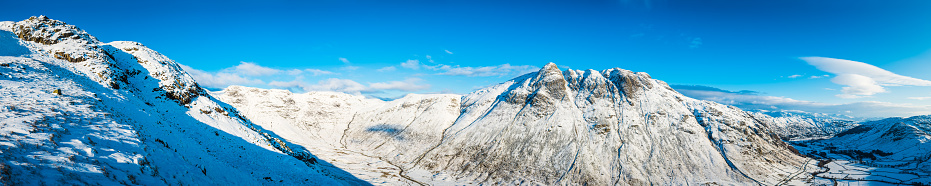 Panoramic view across the Lake District National Park mountains in winter, from the iconic dome of Pike O'Stickle, Pavey Ark and the remote hill farms of Mickleden, down the idyllic Langdale Valley to Elterwater and the snow clad fells of Windermere beyond, Cumbria, UK.