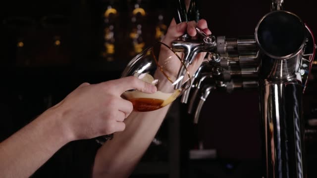 Hand of bartender pouring a large lager beer in tap in a restaurant or pub