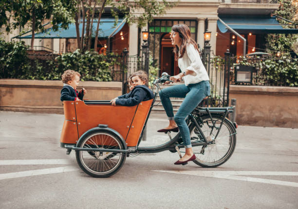 Mother riding bicycle Mother riding bicycle with children on it cargo bike photos stock pictures, royalty-free photos & images