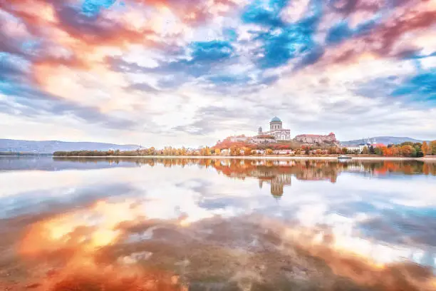 Photo of Esztergom, Hungary - view over Danube river from Sturovo, Slovakia. Epic sunrise landscape with dramatic sky of famous Basilica Esztergom. Amazing reflections of clouds. Red and blue colors scenery.