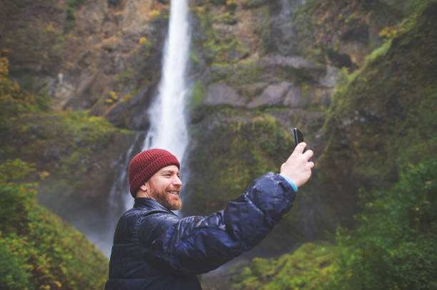 istock Hipster in the rain taking selfies at a waterfall 1066513094