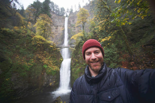 istock Hipster in the rain taking selfies at the Multnomah waterfall personal perspective 1066513100
