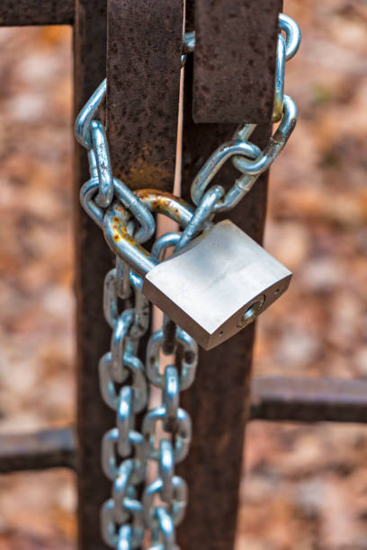 istock Metal silver padlock locked on an iron vintage gate and chain 1066513256