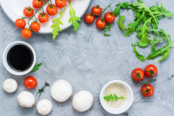 istock Food ingredients lined frame on a concrete background: cherry tomatoes, mushrooms, arugula, sesame and balsamic sauce 1066513682