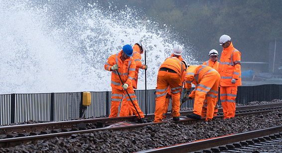 Track ballast shifted by huge waves at Dawlish in Devon after a storm 6th Nov 2018 is being moved back by a maintenance gang of railway workers