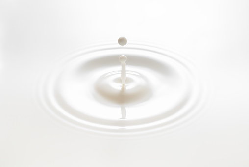 drop falling on milk or white liquid and created splash with circle ripple
