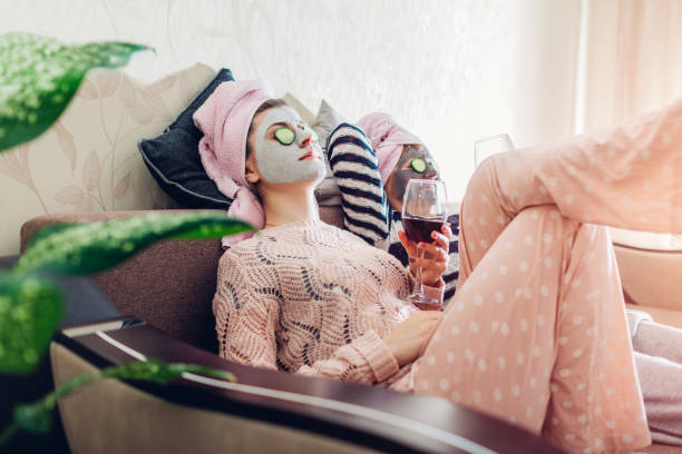 mother and her adult daughter applied facial masks and cucumbers on eyes. women chilling while having wine - facial mask spa treatment cucumber human face imagens e fotografias de stock