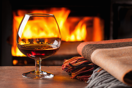 glass of cognac in front of fireplace