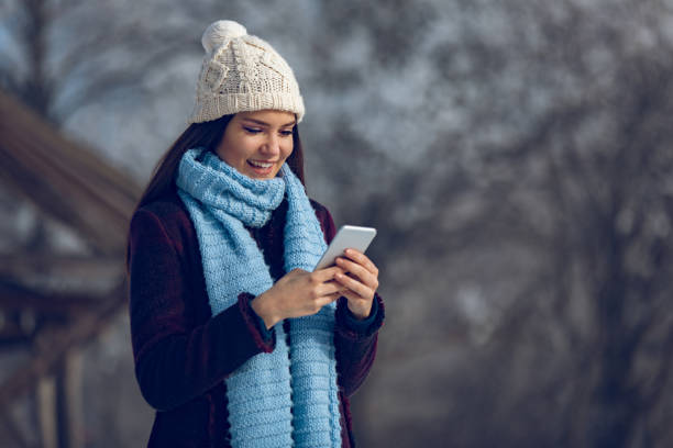 istock Young woman with mobile phone in winter landscape 1066522988