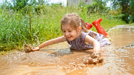 Smiling girl playing in muddy water.