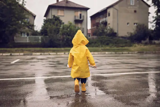 Little boy walking outdoors at rainy autumn day