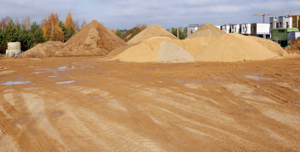 A large piles of construction sand with traces of tractor wheels on city building site. stock photo