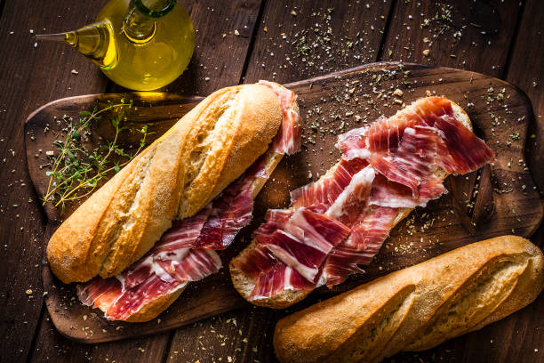 п�риготовление бутерброда с ветчиной иберико, испанский сэндвич из иберийской ветчины - nobody brown wood portion стоковые фото и изображения