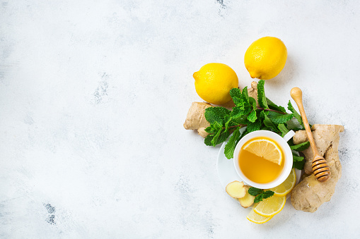 Food and drink, still life health care concept. Ginger tea infusion beverage in white cup with lemon mint honey on a kitchen table for cold and flu winter autumn days. Top view copy space background