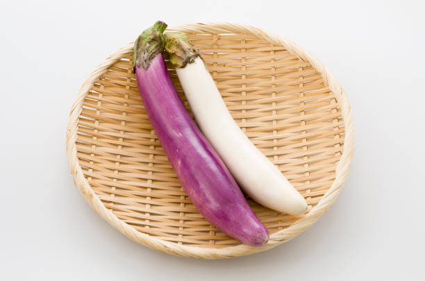 istock Long thin white eggplant and Long thin Purple eggplant on bamboo sieve isolated white background 1066553066