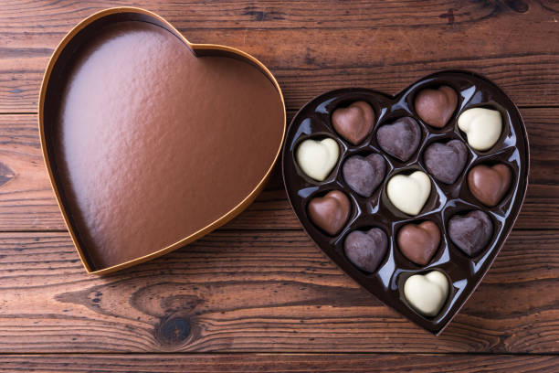 caja en forma de corazón con corazón en forma de trufas de chocolate oscuros y ligeros en mesa de madera - valentines day food photography indoors fotografías e imágenes de stock