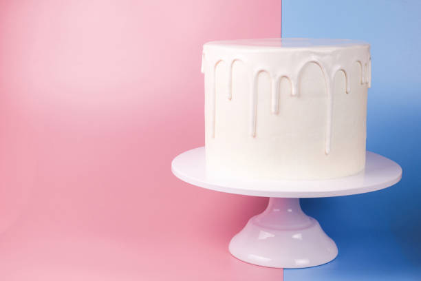 istock Simple white cake with white glaze on a pink and blue background. 1066555504