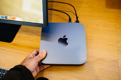 PARIS, FRANCE - NOV 7, 2018: male hand holding new Apple Mac Mini computer with the new processor cpu, 64 DDR4 RAM and 10 Gigabit Ethernet port