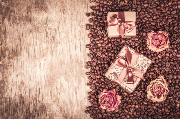 alte hölzerne hintergrund, kaffeebohnen und geschenkboxen.  geschenk mit schleife und bogen, getrockneten rosen und kaffee. romantisches konzept. kaffee geschenk. - coffee bean coffee flower ribbon stock-fotos und bilder