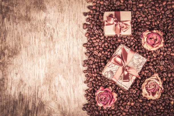 старый деревянный фон, кофейные зерна и подарочные коробки.  пода�рок с лентой и луком, сушеными розами и кофе. романтическая концепция. кофе� - coffee bean coffee flower ribbon стоковые фото и изображения