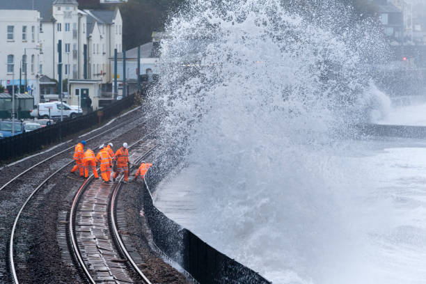 Railway maintenance crew repairing railway track after storm damage On 6th Nov 2018 huge waves battered the Devon coast and caused damage to the train line at Dawlish by shifting the ballast. Here 7 workers are inspecting the track and moving the ballast back to where it should be. ballast water stock pictures, royalty-free photos & images