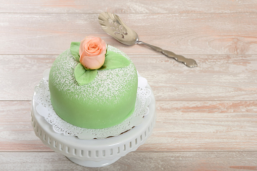 Traditional Swedish princess cake or prinsesstårta made with vanilla sponge cake, creme, raspberry jam and covered with green marzipan.