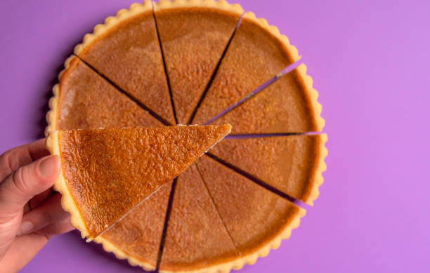 istock Pie slice held in hand over a whole pumpkin pie. Above view 1066569564