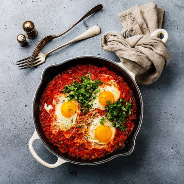 istock Breakfast Shakshuka Fried eggs with tomatoes in frying pan on concrete background 1066570148