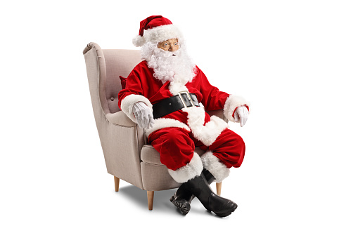 Surprised Santa Claus sitting in an armchair isolated on white background