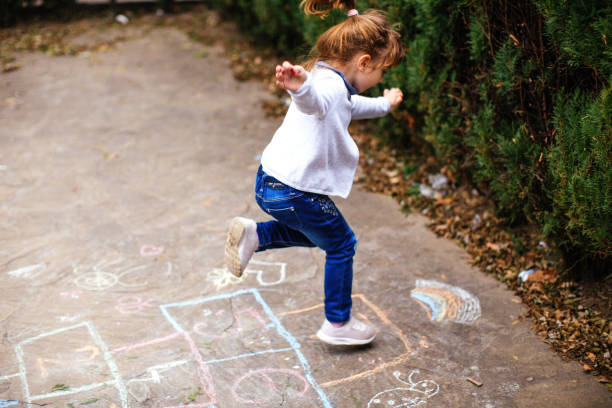 Active little girl enjoying playing hopscotch