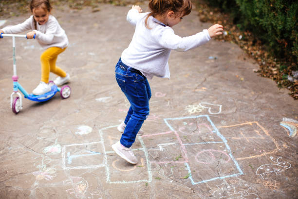 маленькие девочки играют hopscotch на детской площадке - hopscotch стоковые фото и изображения