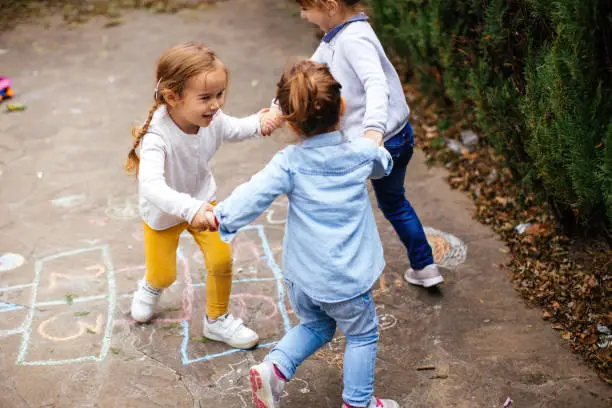 Toddler friends playing hopscotch outdoors