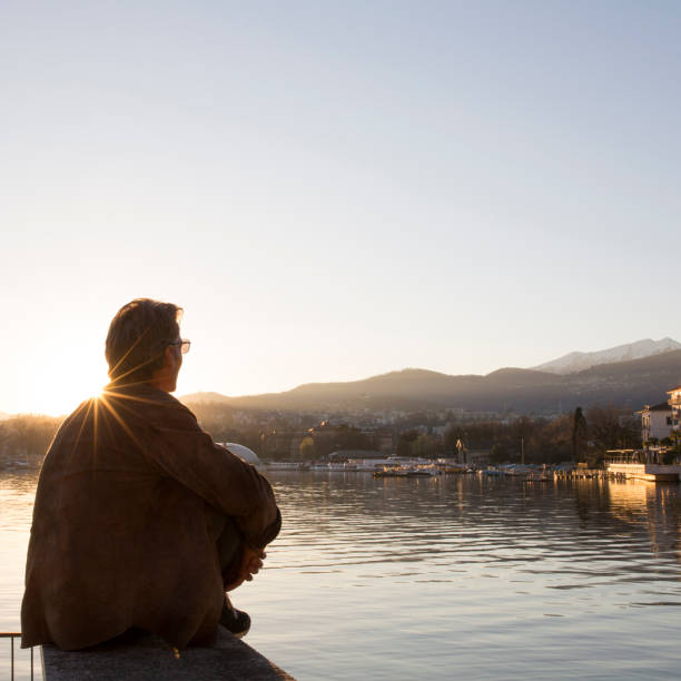 istock Man enjoys sunrise over lake and Lugano 1066591220