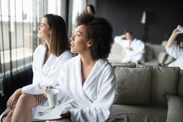 mujeres relajarse y beber té en trajes durante el fin de semana welness - bathrobe women cup towel fotografías e imágenes de stock