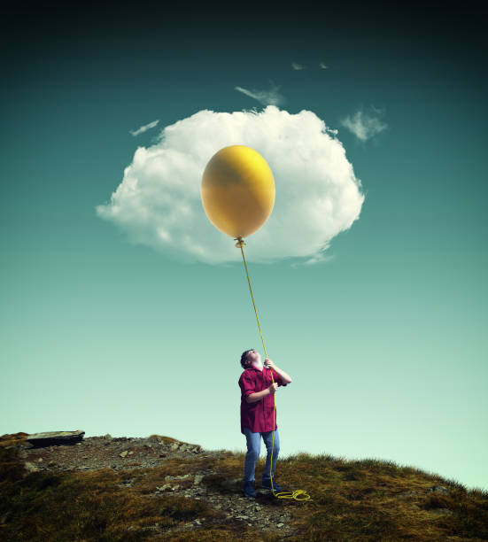istock Young man raising up a yellow balloon to a cloud, looking like a fried egg. 1066603440
