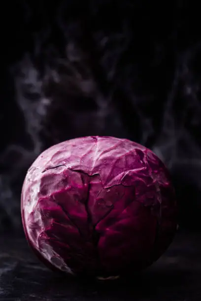 Whole red cabbage on dark wooden background