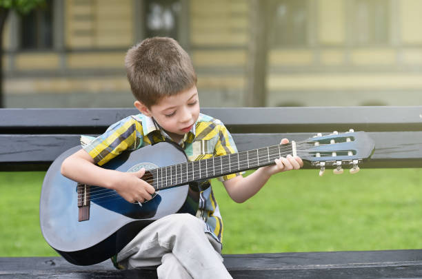 istock child boy playing on guitar in a park 1066608730