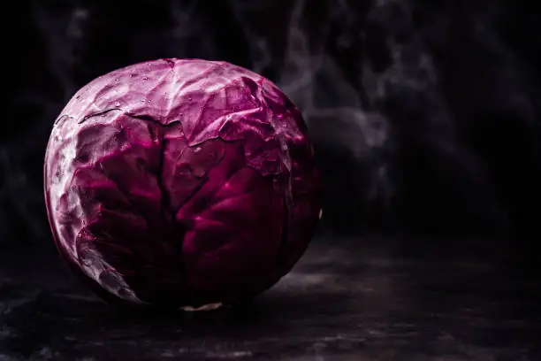 Whole red cabbage on dark wooden background