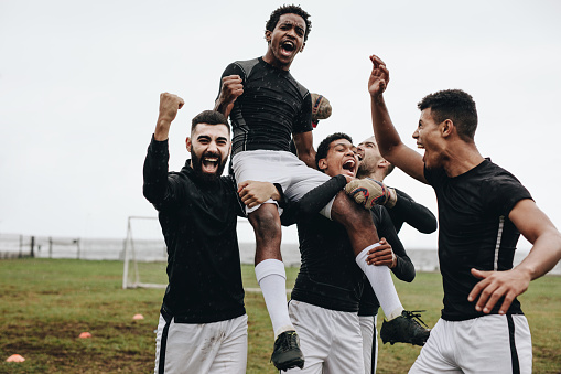 Happy group of Latin American soccer players celebrating a victory in the field - sports concepts