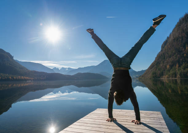 Athletic Man pushing a Handstand on a pier by the beautiful Lake Altaussee with the famous Dachstein Glacier in back, Austrian Alps, Austria. Nikon D850. Converted from RAW.