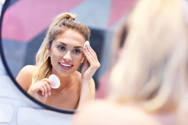 istock Young woman cleaning face in bathroom mirror 1066626458